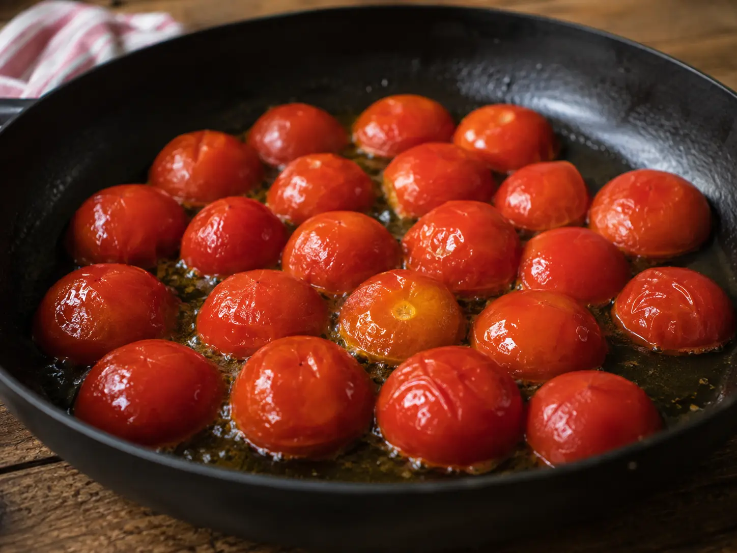 Tomates coupées en deux saisies face coupée dans l'huile d'olive chaude