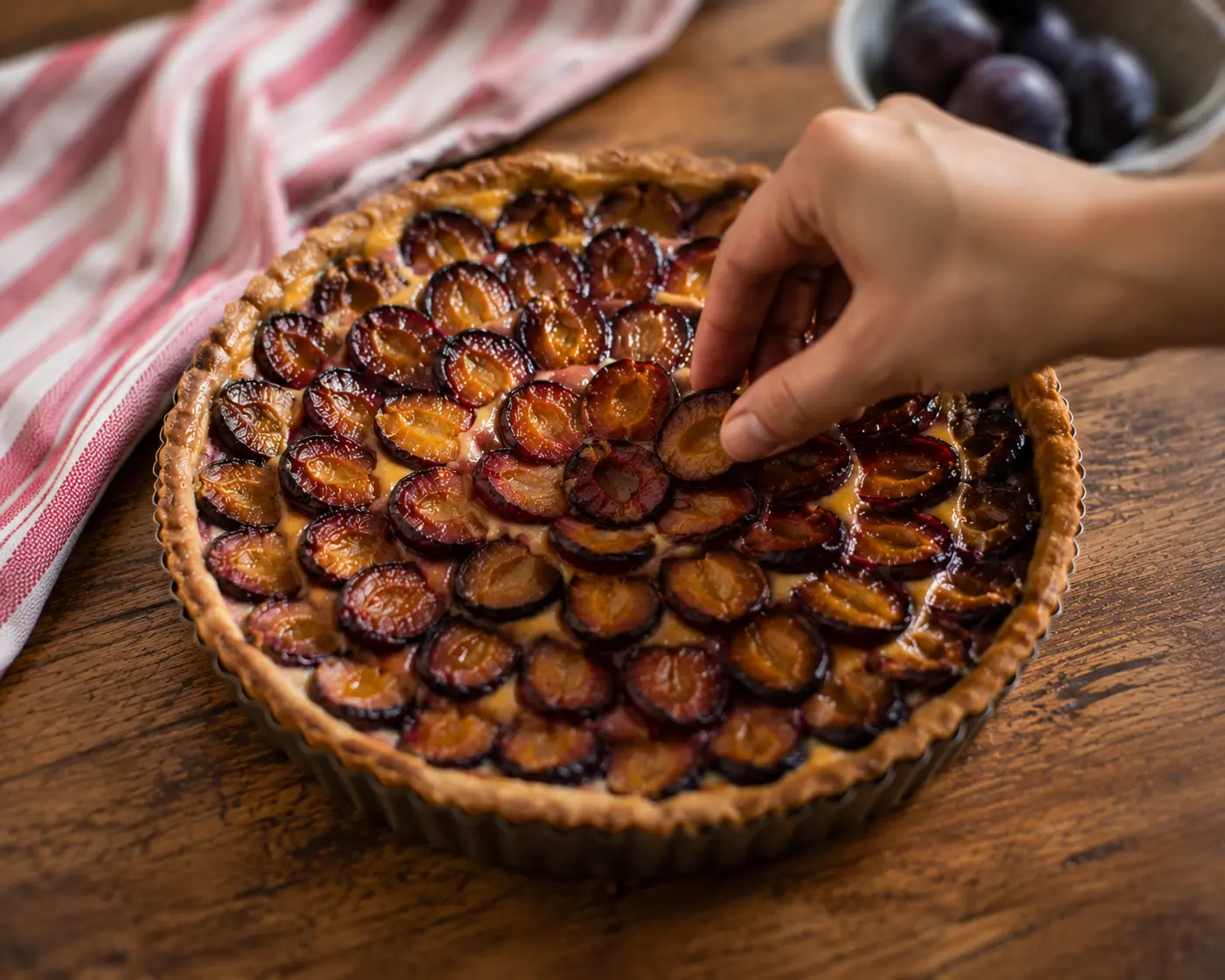 Prunes coupées en deux disposées face coupée vers le haut sur le fond de tarte