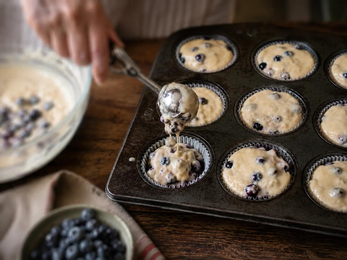Pâte à muffins garnie de bleuets répartie dans le moule avant la cuisson