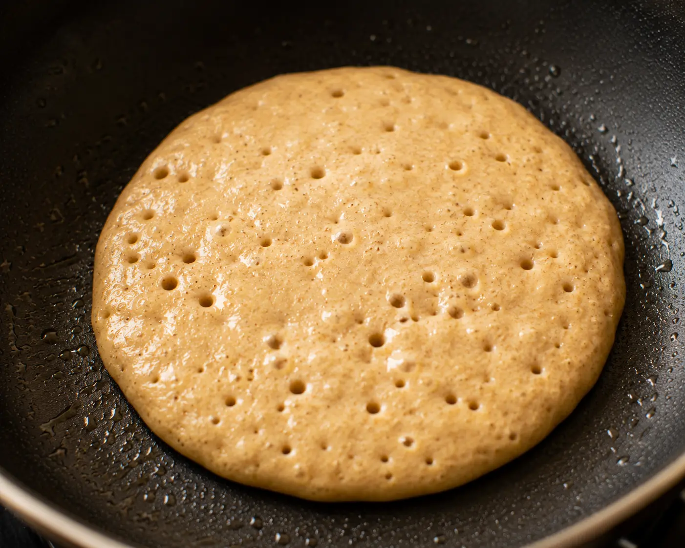 Pancake avec bulles en surface prêt à être retourné
