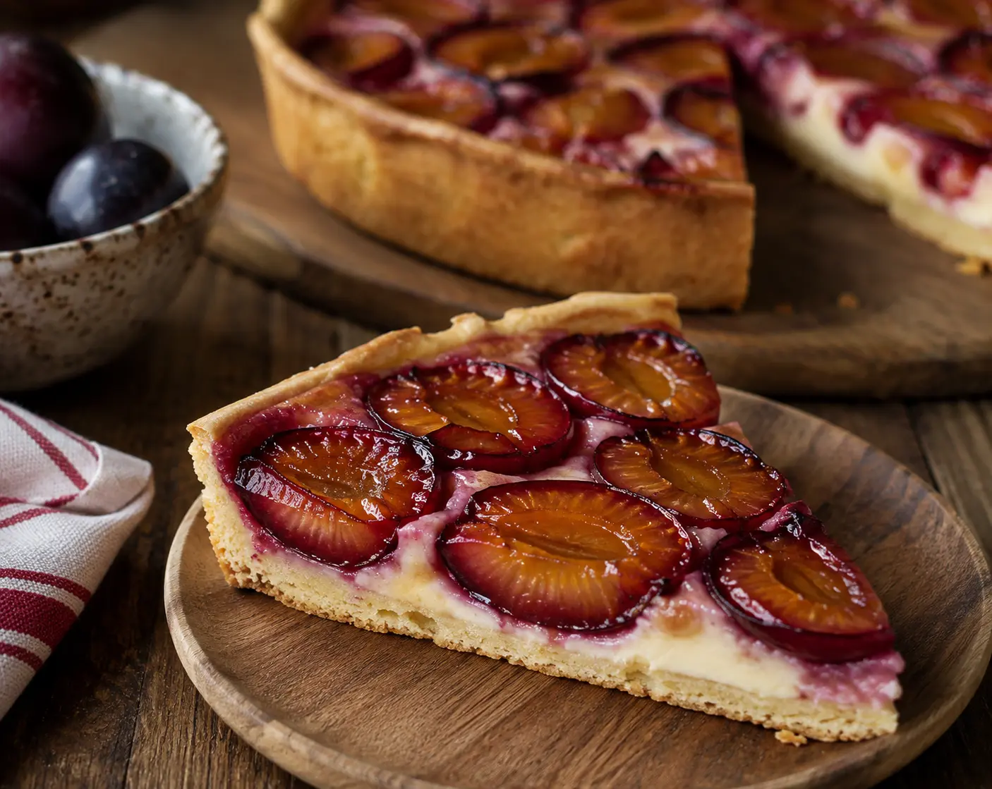 Part de tarte aux prunes découpée révélant la pâte croustillante et les fruits fondants