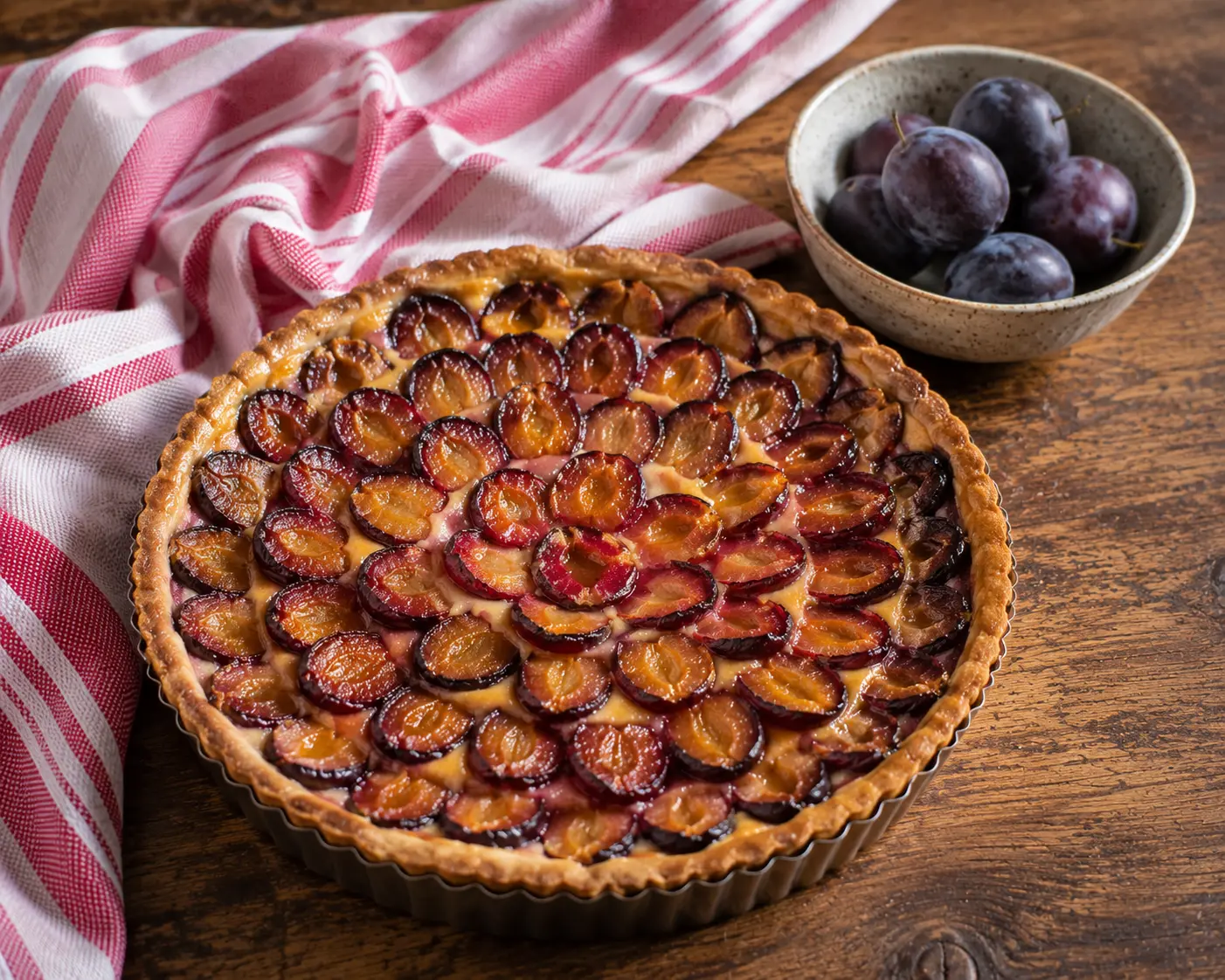 Tarte aux prunes entière avec fruits disposés en cercles concentriques